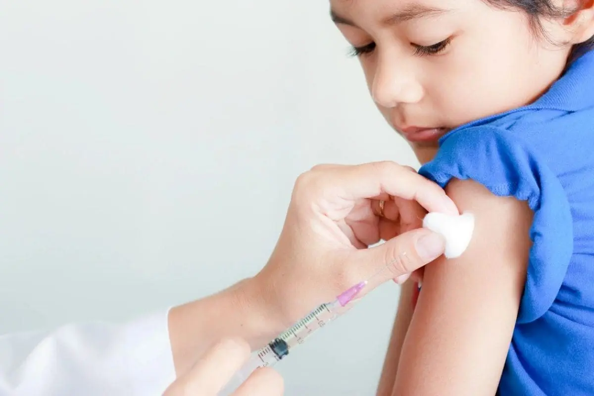 A child getting an injection from someone else.