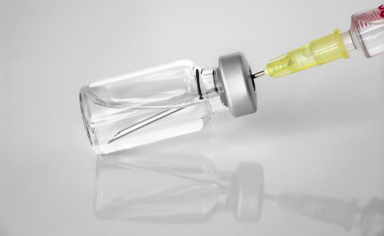 A glass bottle with a yellow top and a metal cap.