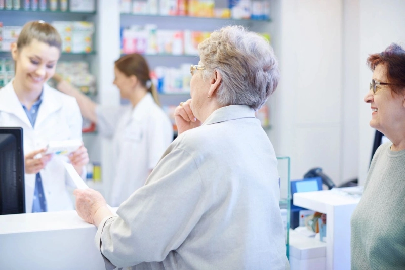 A woman in white shirt and gray jacket standing next to a counter.